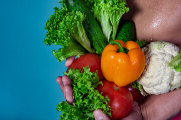 Slim male body and fresh vegetables. Healthy food and sports. Diet and weight loss. Blue background.