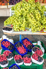 Large bunches of succulent green grapes displayed above tubs of raspberries at Kotor market,Montenegro,Eastern Europe.