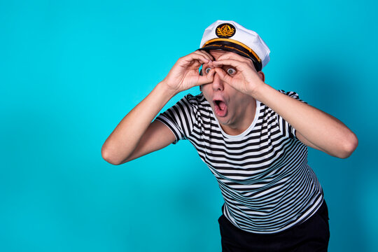 Funny experienced sailor ready for marine travel. Cheerful young sailor. Expression of emotions. The guy is posing on a blue background.