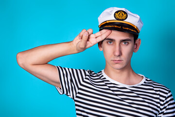 Funny experienced sailor ready for marine travel. Cheerful young sailor. Expression of emotions. The guy is posing on a blue background.