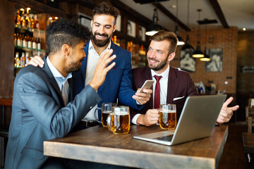 Happy young businessmen in suits are smiling and talking in a restaurant