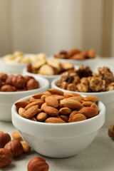 Bowls with different nuts on white textured background, space for text