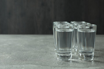 Shots with vodka on gray background, space for text