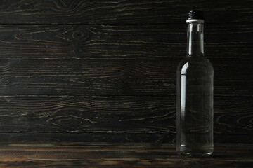 Blank bottle of vodka on wooden background, space for text