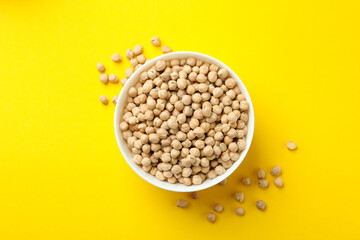Bowl with fresh chickpea on yellow background
