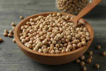 Bowl, jar and spoon with chickpea on gray table