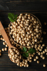Bowl and spoon with chickpea on wooden table