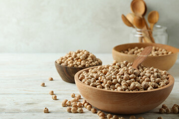 Bowls and spoons with chickpea on white wooden table