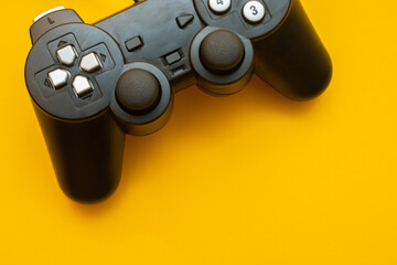 Crop close up black joystick gaming controller on trendy yellow background with space for text:...