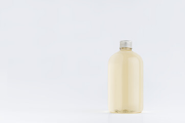 Transparent plastic low thick bottle with pale fresh drink or cosmetic essential oil with silver cap mockup on white background, template, copy space.