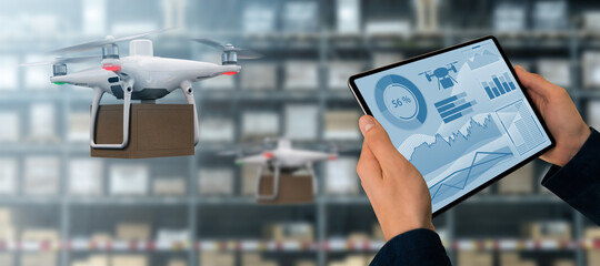 Warehouse manager with digital tablet controls drone with a package. Unmanned delivery concept