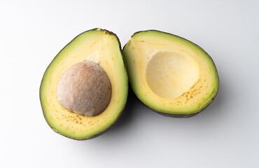 Avocado cut in half isolated on a white background, the flesh of the avocado is creamy and soft with a buttery taste. Avocados contain nutrients, vitamins and good fats.