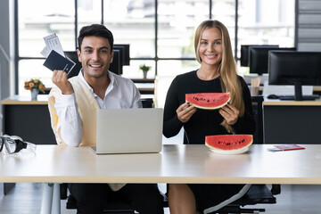 Attractive Caucasian business people eating watermelon in office. Summer vacations concept.