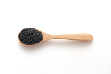 Black sesame in wooden spoon isolated on a white background, top view.