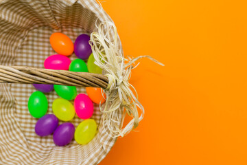 Fototapeta na wymiar Wicker basket with colorful Easter eggs on yellow background.Copy space.