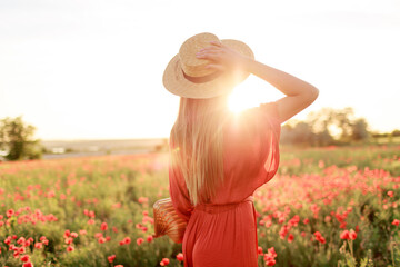 photo from back of inspired  young woman holding straw hat and looking at horizon. Freedom concept....