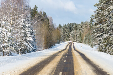 Obraz premium Winter road in snowy forest on a sunny day.