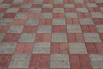 the sidewalk is paved with pink and gray tiles.