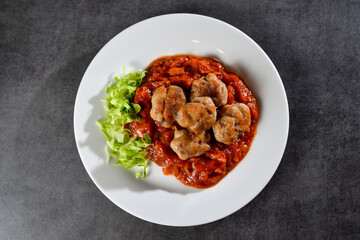 Homemade chicken meatballs in tomato sauce on dark stone or concrete table