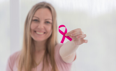 Woman holding pink ribbon the symbol of breast cancer and smile for supported the cancer patient