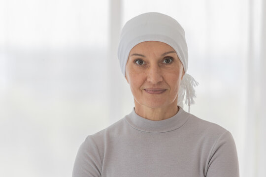 Middle-aged Woman Cancer Patient Lost Hair From Chemo Cure Process And Use Clothe Cover Her Head Posing To Camera With Strength Eyes And Emotion