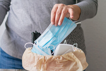A person throwing a disposable mask into a trash can