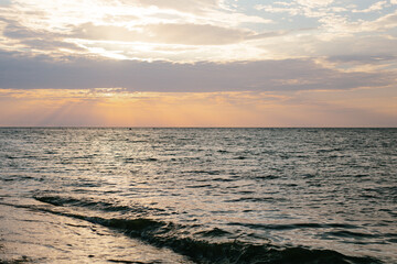 Sunset by the sea. Warm colors. There are no people. The photo is horizontal, color.