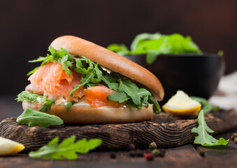 Organic healthy sandwich with salmon and bagel, cream cheese and wild rocket on wooden board