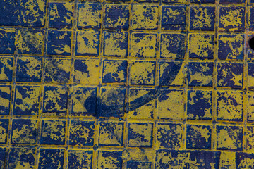 The texture of a manhole cover drenched in yellow paint.