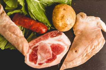 ingredients of the Galician stew recipe during carnivals consisting of potato, pork leg, lacon, smoked ear, chorizo ​​and turnip greens