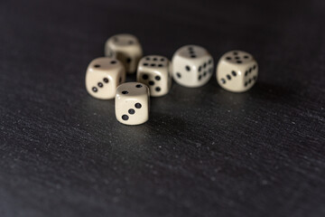 Several dice lie on a neutral, dark stone slab.