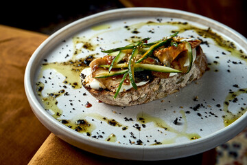 Bruschetta with eel, cucumber and cream cheese on rye bread, served in a white plate. Restaurant food. View from above. Italian Cuisine