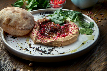 Appetizing French dish - chicken pate with onion jam and pita bread served in a white plate on a wooden background. Close up view