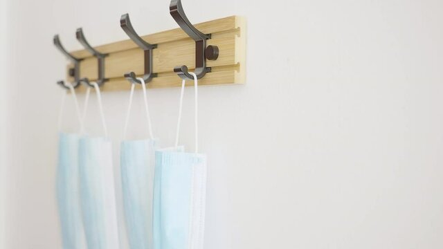 Person hand put the surgical mask back on hang hook close-up 4K