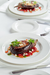 Half baked eggplants with meat, cheese and tomatoes on white background. Banquet festive dishes. Gourmet restaurant menu. White background.