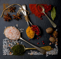 Various spices spoons on black table. Top view with copy space