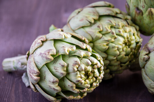 Close-up of several green artichokes, with selective focus, on wooden table, horizontal
