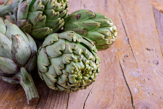 Top view of green artichokes, with selective focus, on rustic wooden table, horizontal, with copy space