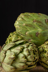 Obraz premium Close-up of a group of green artichokes, with selective focus, black background, vertical, with copy space