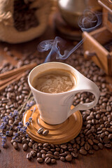 cup of coffee and coffee beans in a sack on dark background, top view