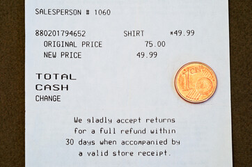 one euro cent coin over a receipt showing sale discount 