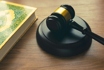 Sharia or Islamic law concept with gavel and Quran on wooden background.