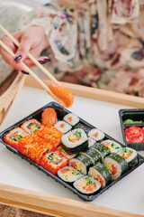 Girl eating sushi. Sushi delivery concept, sushi in plastic container delivered to home