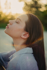 Portrait of young woman with closed eyes at sunset.