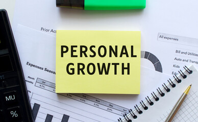Fototapeta premium Text PERSONAL GROWTH on the page of a notepad lying on financial charts on the office desk.