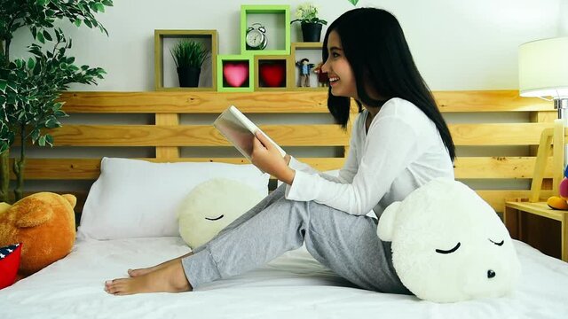 Relax asian woman reading book sitting on sofa in living room holding book to read. Young woman relaxation reader reading open book leisure mind. Happiness beauty woman person smiling face happy time