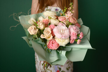 Woman holding a beautiful bouquet with flowers on green background. Front view. Valentine's,...