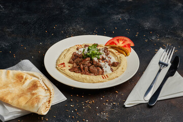 Creamy hummus with spicy mutton minced meat on dark background