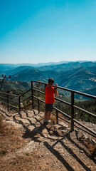 The boy admires the beautiful high-altitude landscape in the way of the road. Rest, hiking in the mountains, traveling.