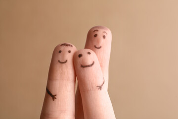 Three fingers with drawings of happy faces on brown background. Family time